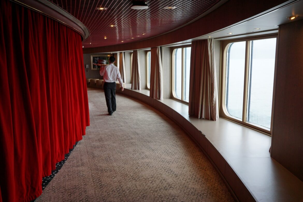 a man in a white shirt is walking down a hallway